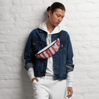 Mann in Jeansjacke und weißem Hoodie mit einer gemusterten Bauchtasche vor weißer Ziegelwand