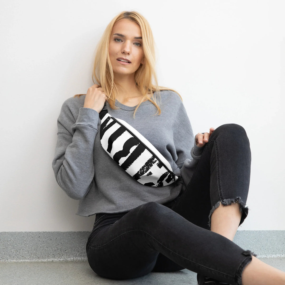 Frau in grauem Sweatshirt und schwarzen Jeans mit schwarz-weiß gemusterter Gürteltasche