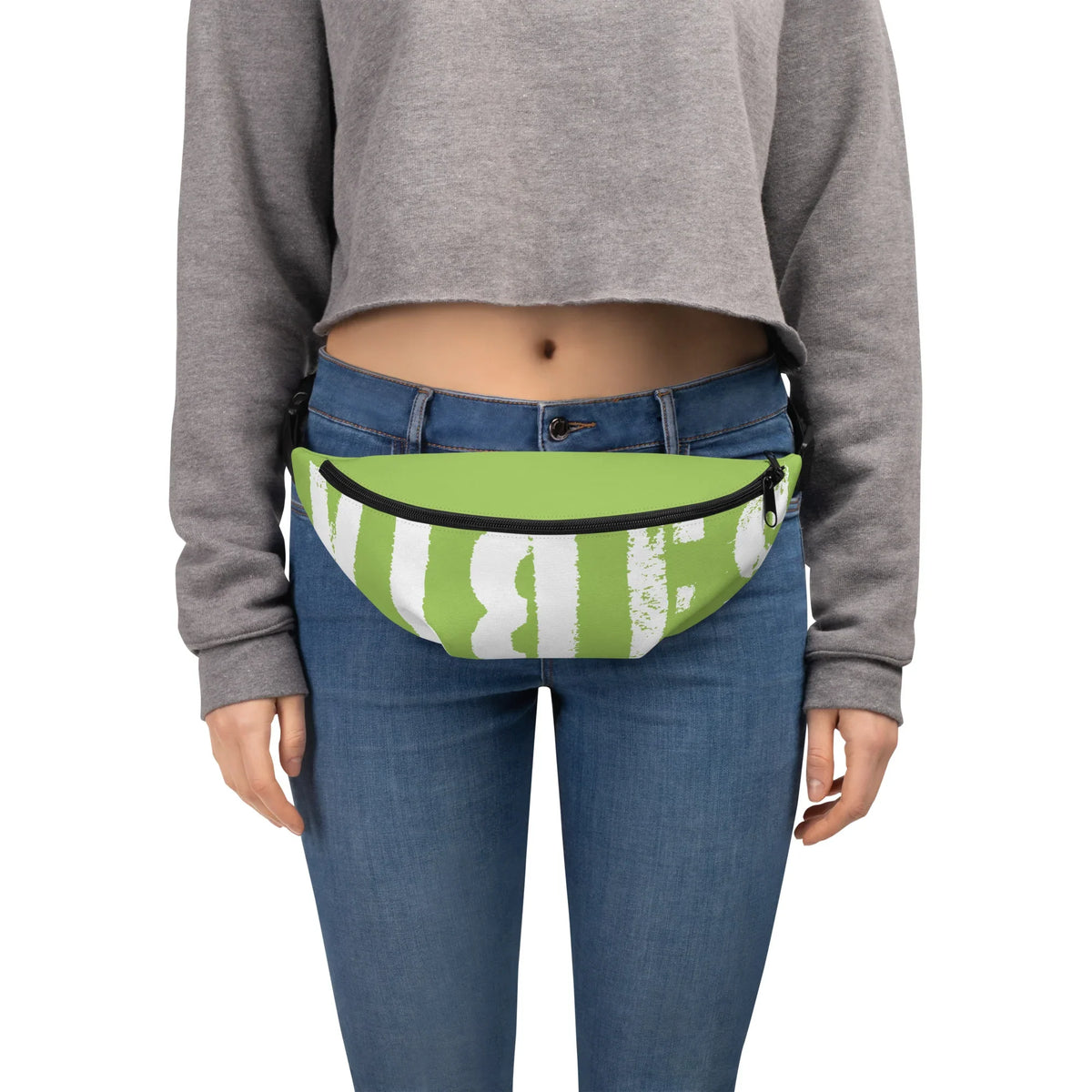 Grüne Bauchtasche mit weißem Grafikprint an einer Person mit Jeans und grauem Crop-Sweatshirt