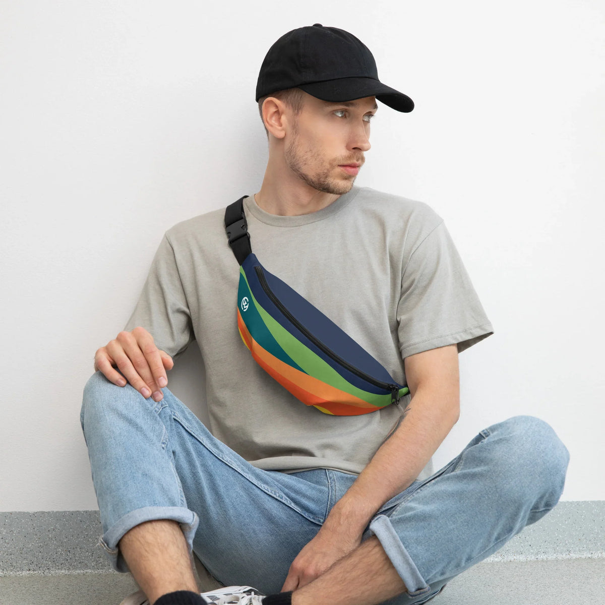 Mann mit grauem T-Shirt, schwarzer Kappe und einer bunten, gestreiften Bauchtasche
