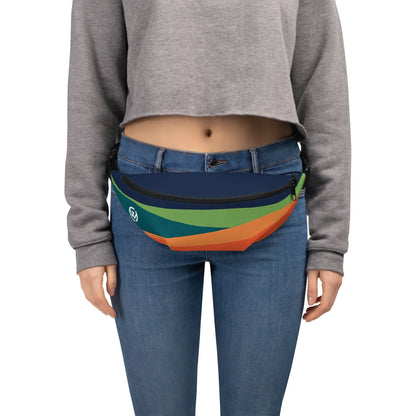 Person trägt eine mehrfarbige Bauchtasche in Blau, Grün und Orange zu Jeans und grauem Sweatshirt.