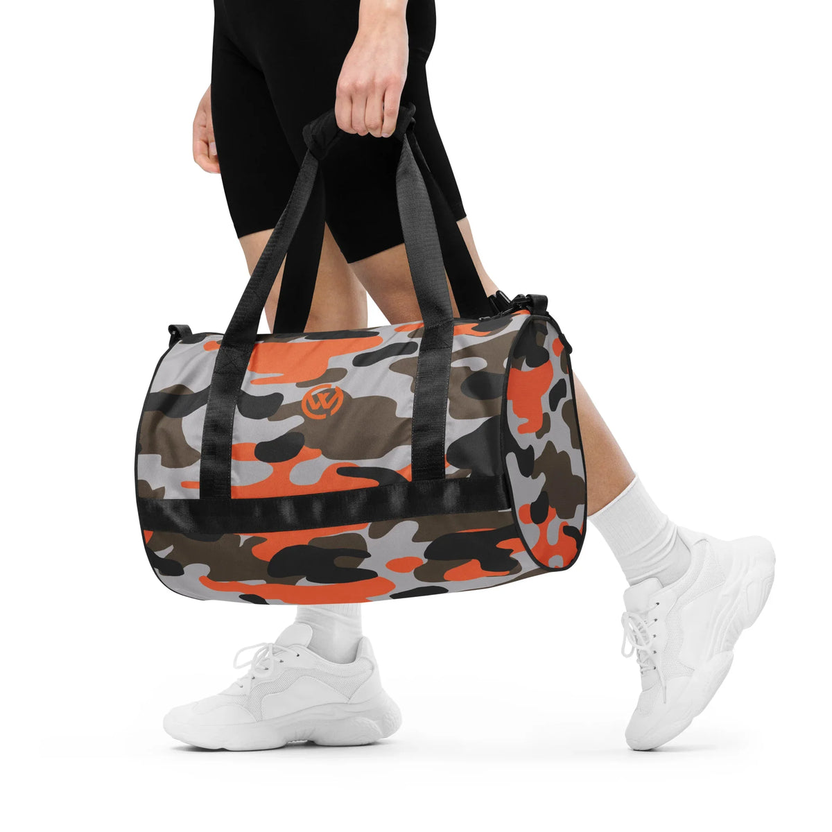 Person trägt eine CREWILD Sporttasche mit grau-orangem Camouflage-Muster.