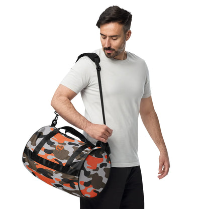 Mann trägt eine CREWILD Sporttasche im orange-grauen Camouflage-Design.