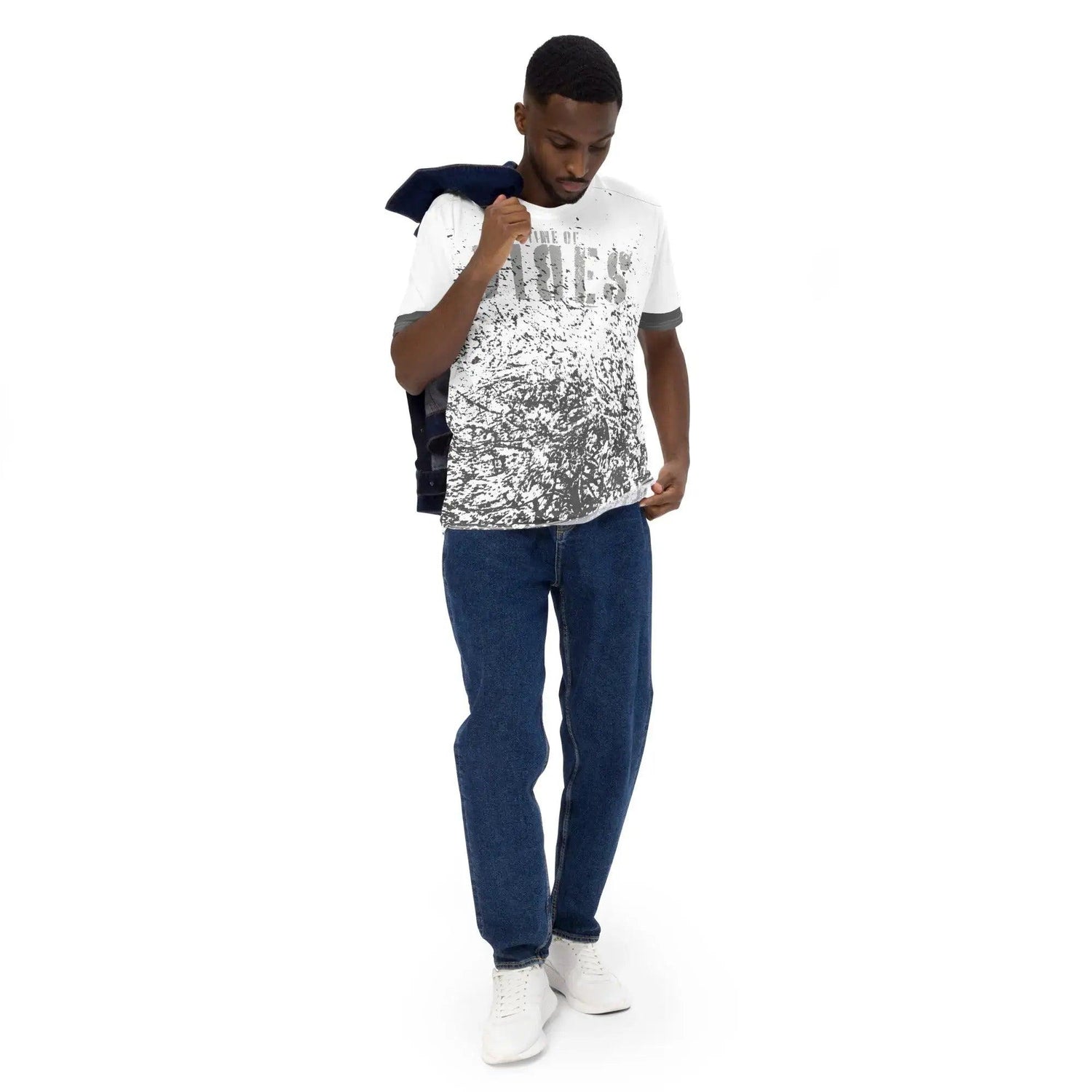Mann trägt weißes Allover-Print T-Shirt, blaue Jeans und weiße Sneaker vor weißem Hintergrund.
