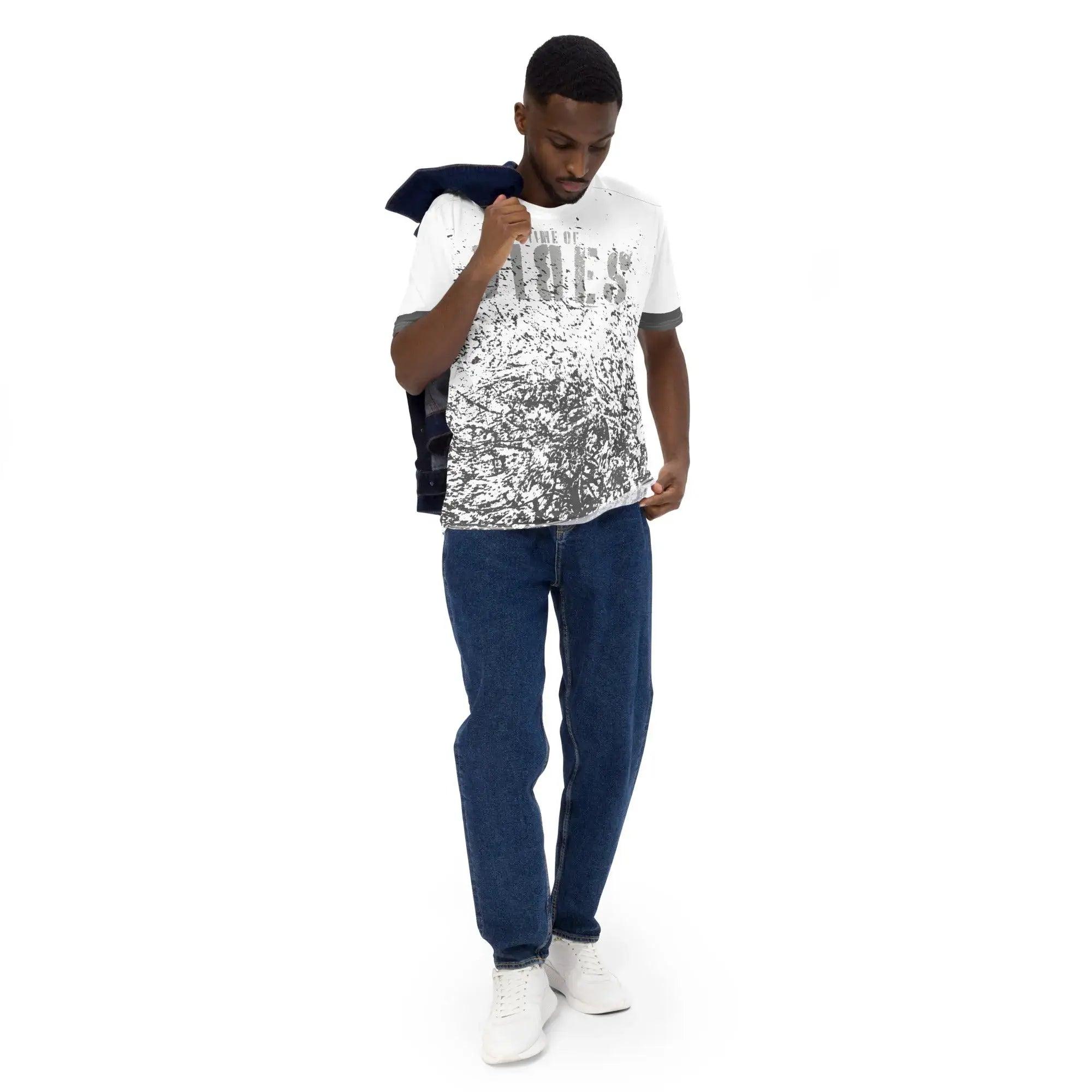 Mann trägt weißes Allover-Print T-Shirt, blaue Jeans und weiße Sneaker vor weißem Hintergrund.