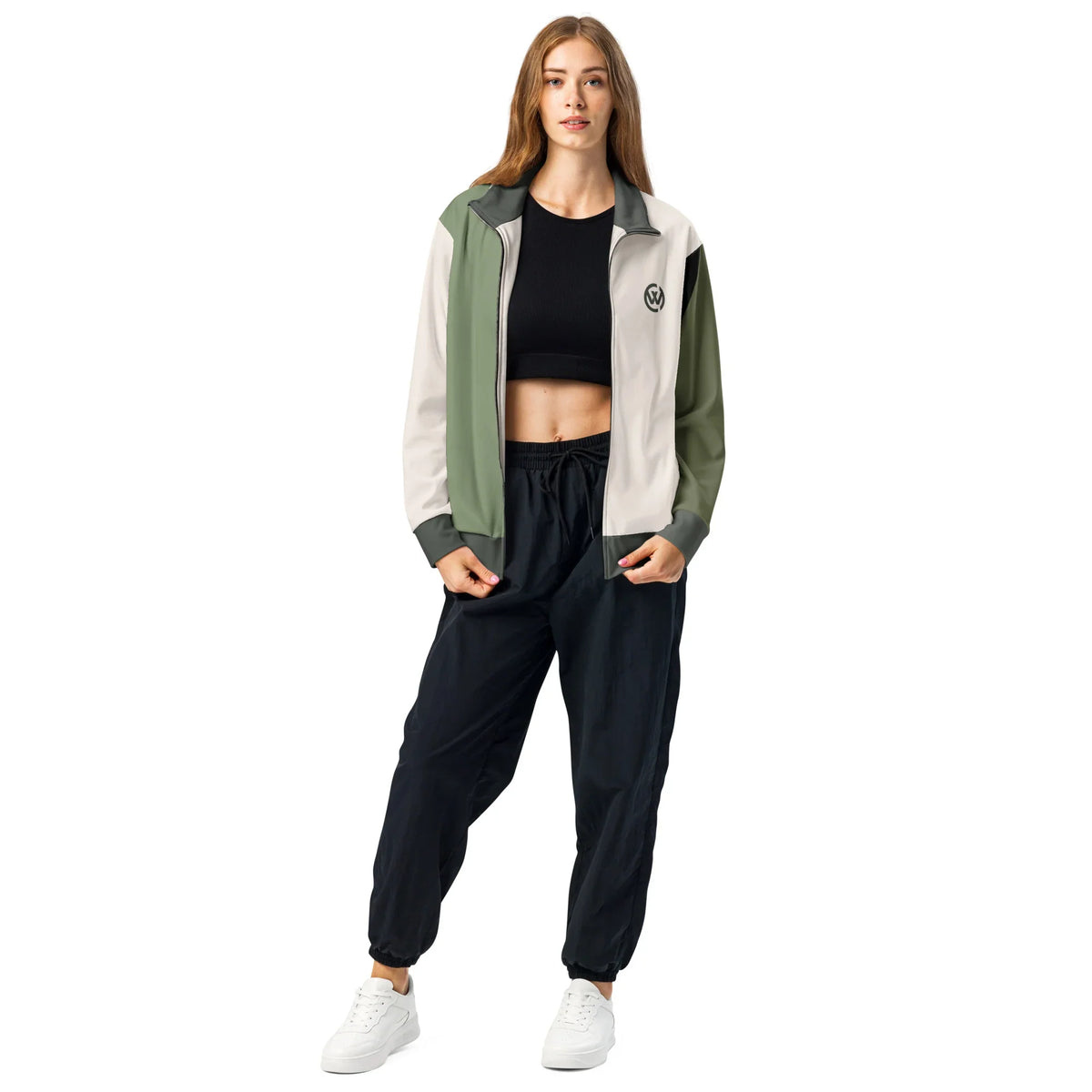 Frau in CREWILD Jacke in Creme und Grün, kombiniert mit schwarzem Crop Top und Jogginghose.