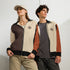 Zwei Personen tragen die Unisex CREWILD Jacke in Braun und Creme mit Logo.