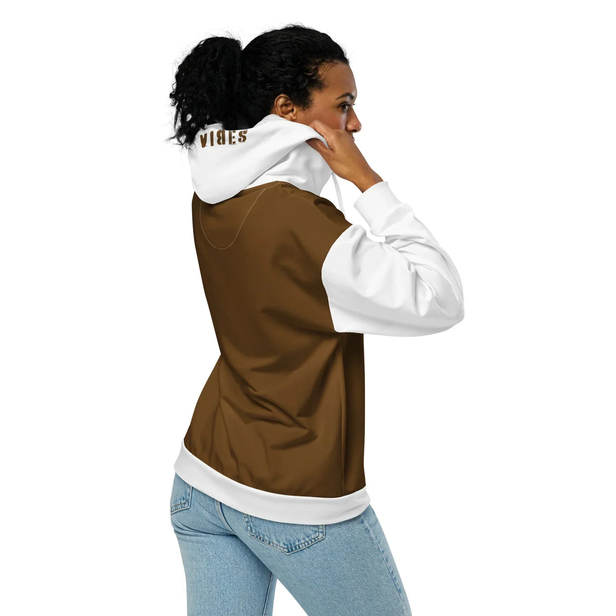 Frau von hinten im braun-weißen CREWILD Zip-Hoodie mit VIBES-Stickerei auf der Kapuze.