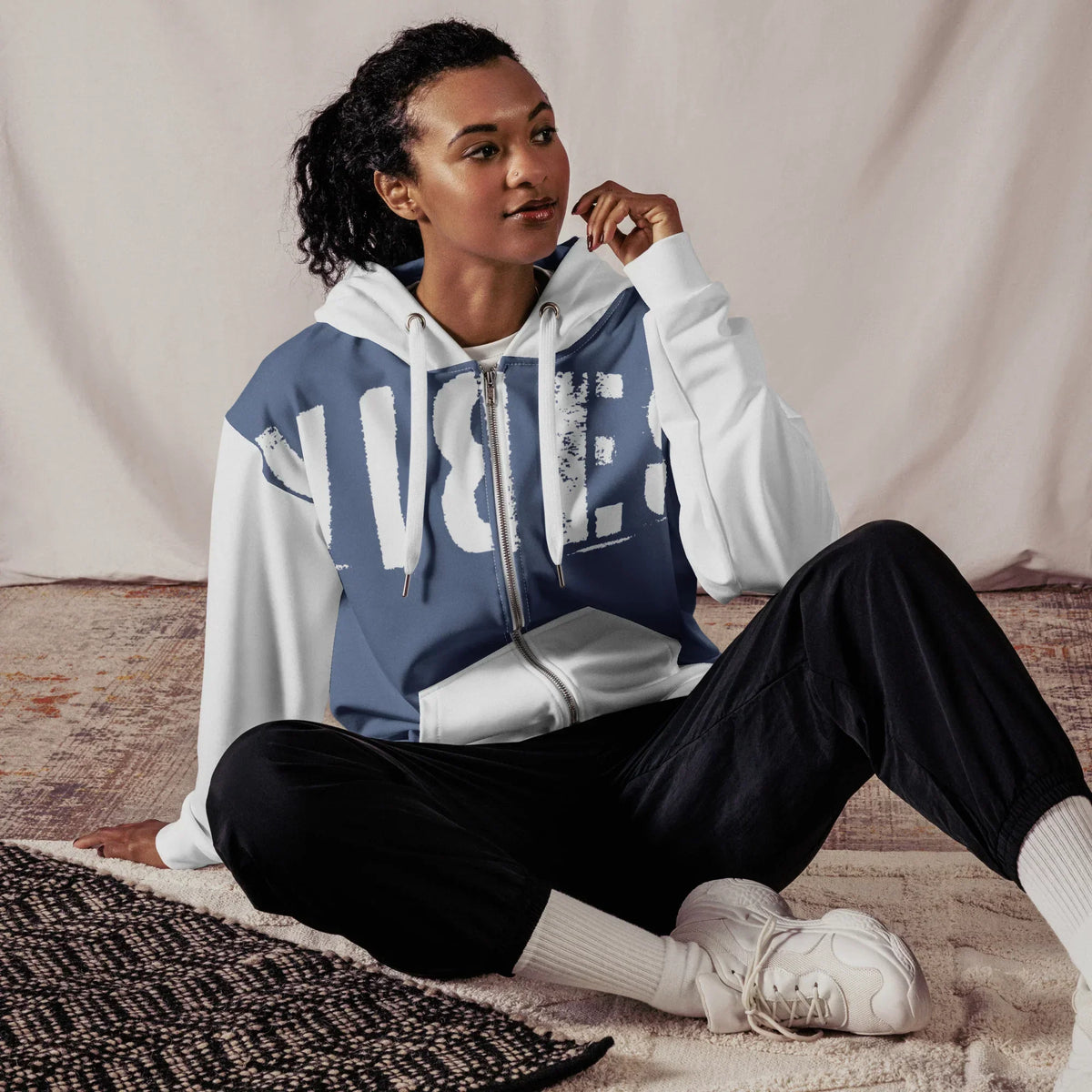Frau im mittelblau-weißen CREWILD Zip-Hoodie mit VIBES-Print und schwarzen Hosen.