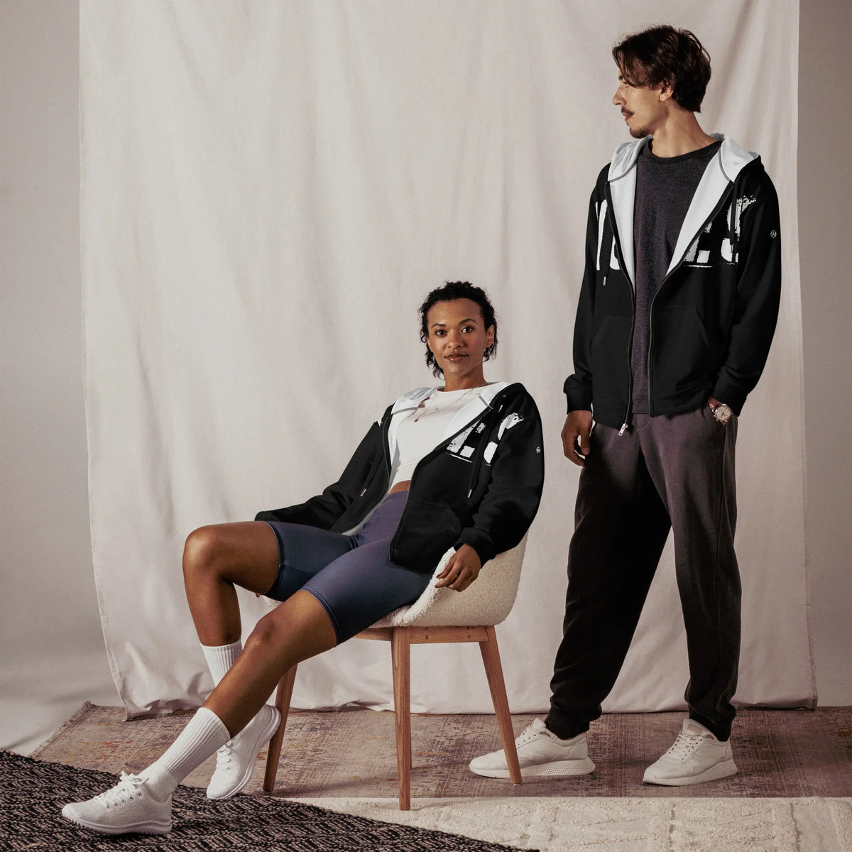 Personen in personalisierten schwarzen Hoodies und Sportbekleidung vor hellem Hintergrund.