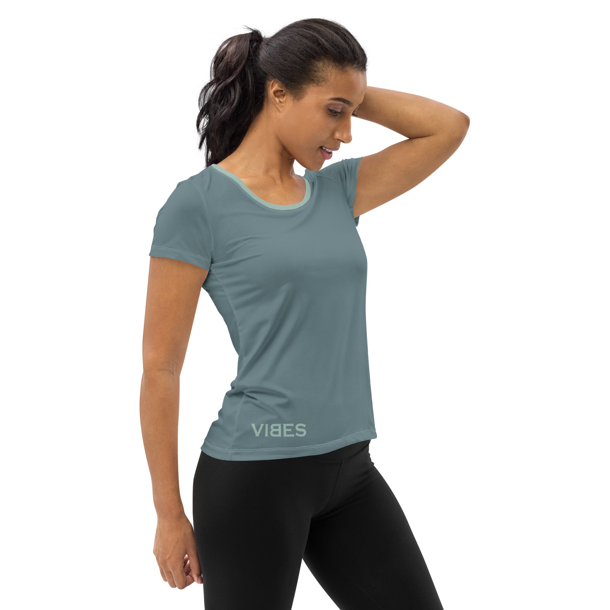 Frau im sportlichen, grauen Damen-T-Shirt mit Vibes-Aufdruck und schwarzen Leggings, Studioaufnahme