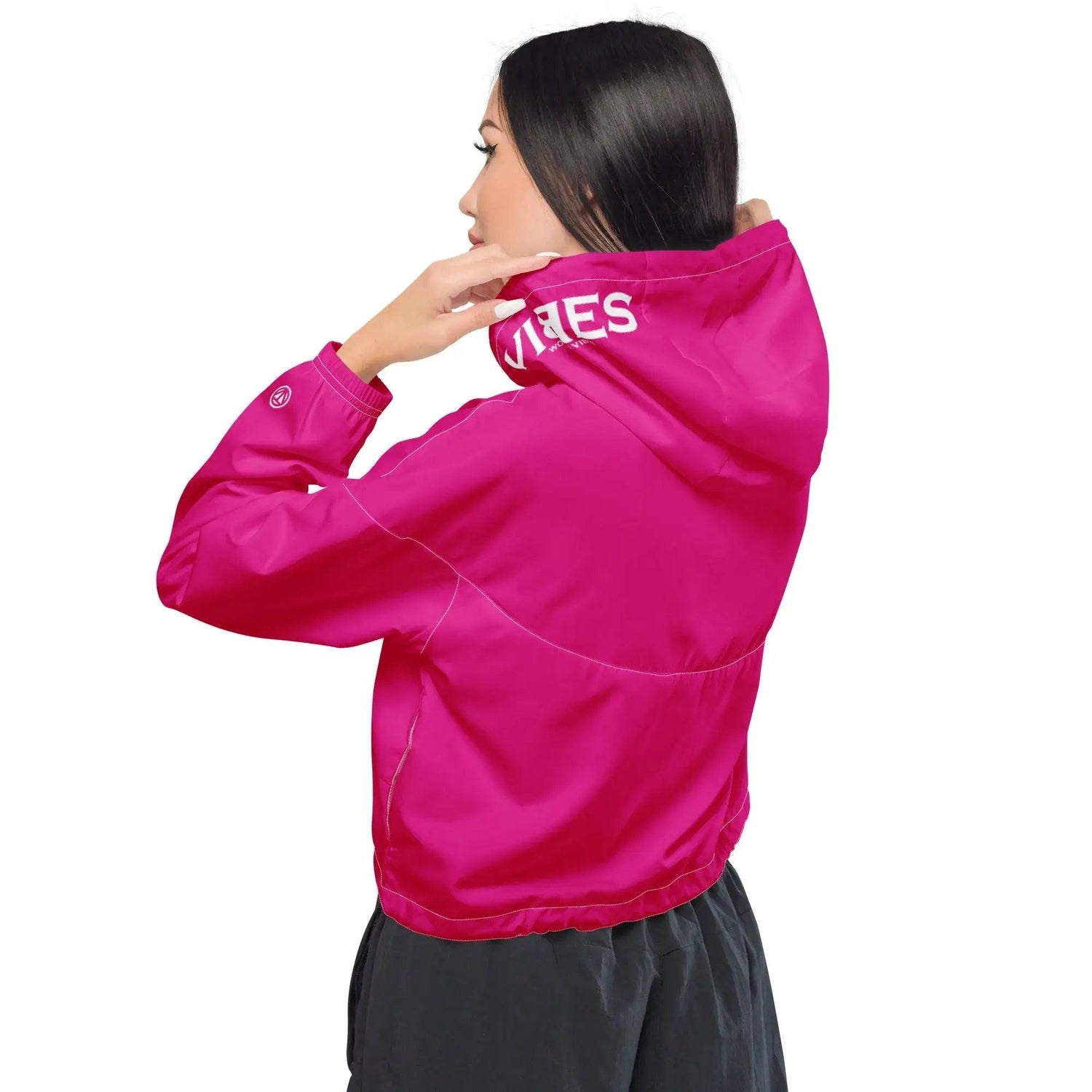 Frau mit pinker Cropped-Windjacke und Kapuze, Rückansicht, auf weißem Hintergrund