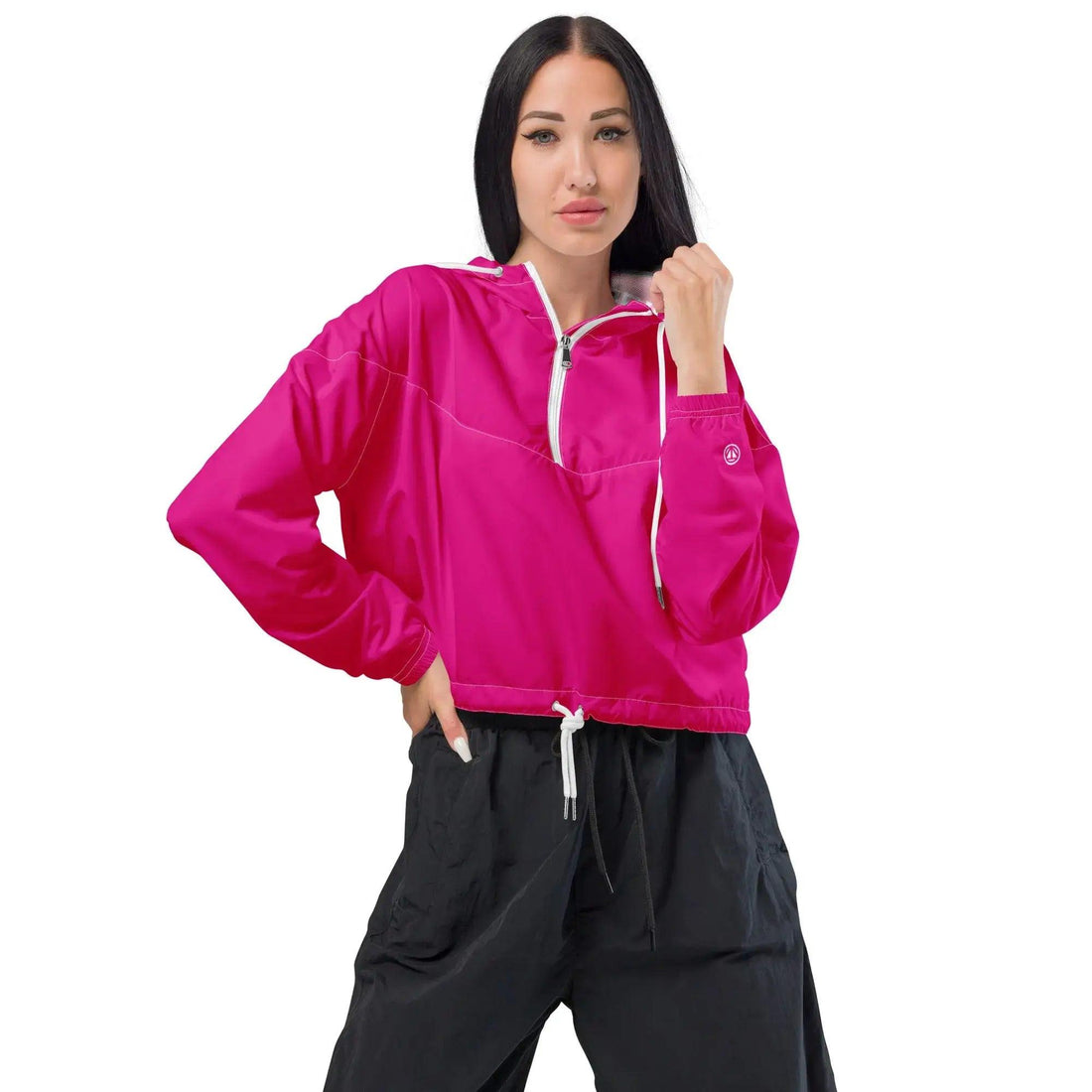 Frau trägt pinke Cropped Windbreaker Jacke mit weißen Kordeln und schwarzen Hosen vor weißem Hintergrund.
