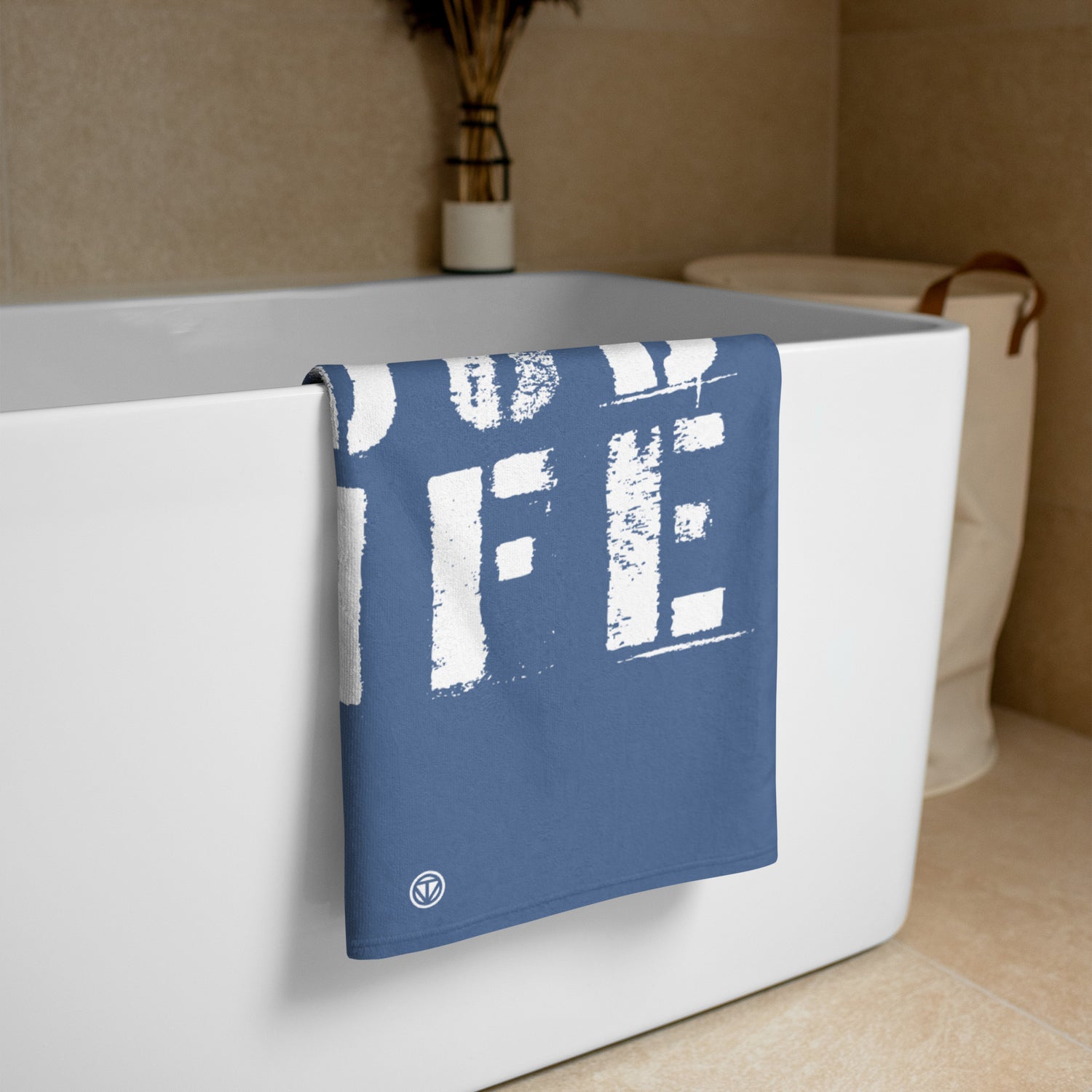 Blau-weißes Handtuch mit aufgedrucktem Schriftzug hängt an einer weißen Badewanne in modernem Badezimmer