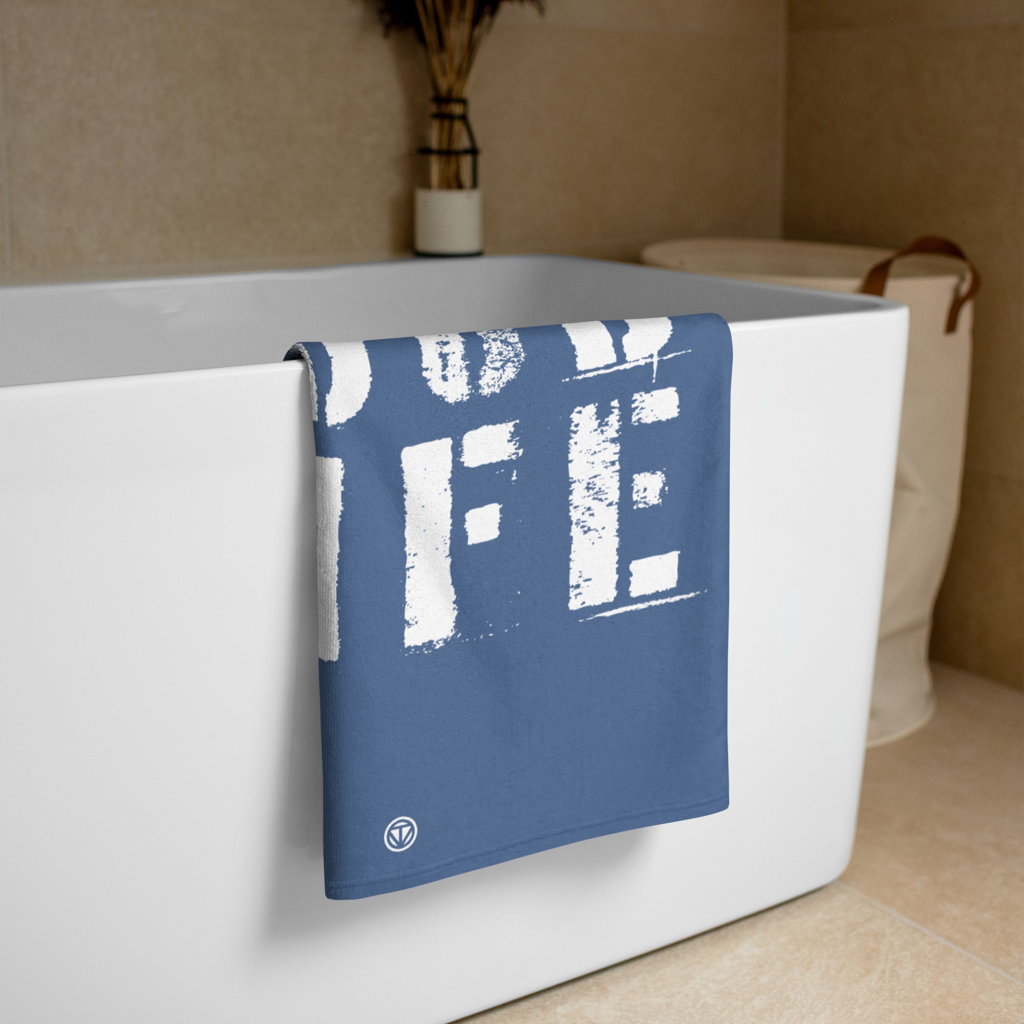 Blau-weißes Handtuch mit aufgedrucktem Schriftzug hängt an einer weißen Badewanne in modernem Badezimmer