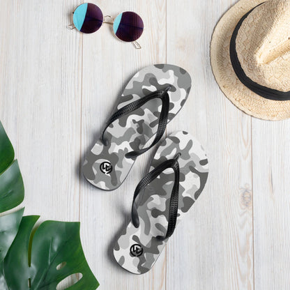 Graue CREWILD Flip-Flops mit Camouflage-Muster auf hellem Holzhintergrund mit Sonnenbrille und Hut.