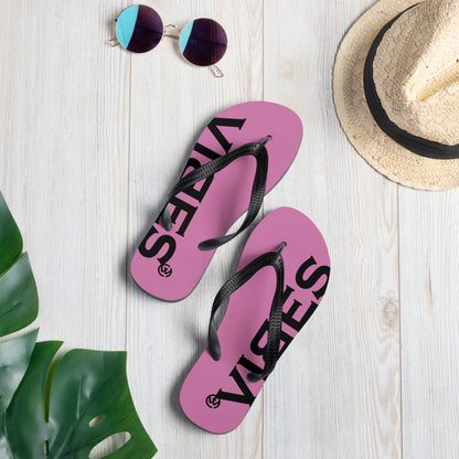 Pinke CREWILD Flip-Flops mit schwarzem VIBES-Schriftzug auf hellem Holzhintergrund
