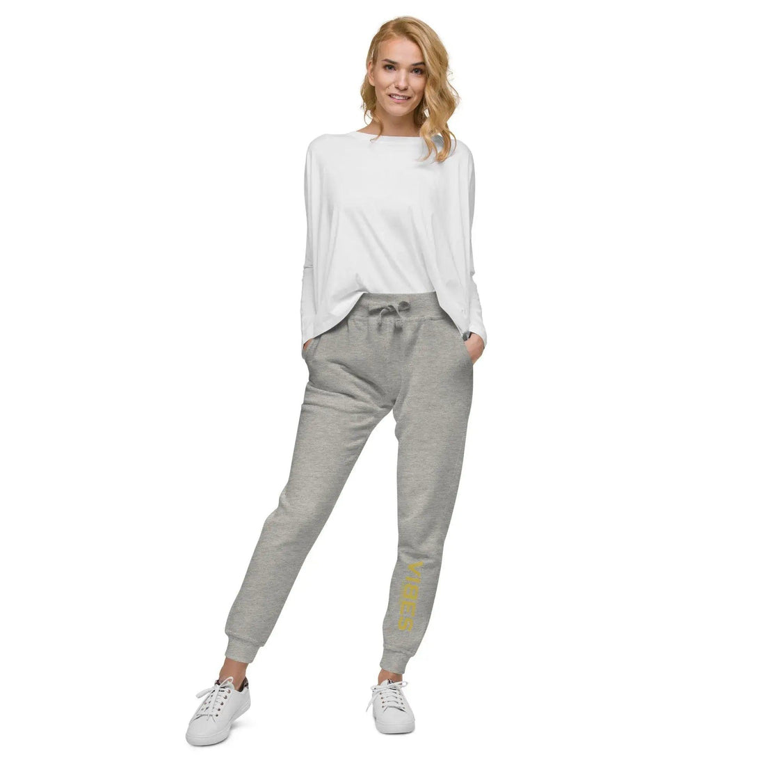 Frau trägt graue Unisex-Fleece-Sweatpants mit gelbem Aufdruck, weißes Sweatshirt