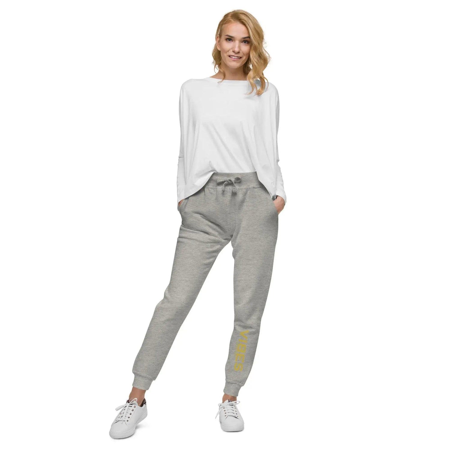 Frau trägt graue Unisex-Fleece-Sweatpants mit gelbem Aufdruck, weißes Sweatshirt