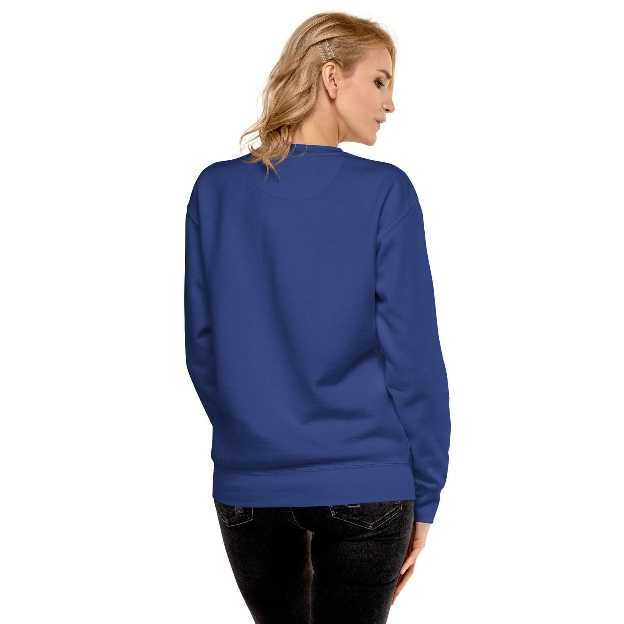 Frau trägt blauen Unisex Premium Sweatshirt, Rückenansicht, vor weißem Hintergrund.