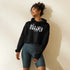 Frau trägt schwarzen CREWILD Crop-Hoodie mit weißem München-Schriftzug und graue Biker-Shorts.