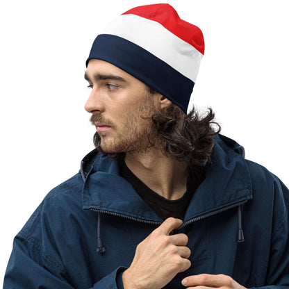 Mann mit Beanie in Rot-Weiß-Blau und blauer Jacke vor weißem Hintergrund