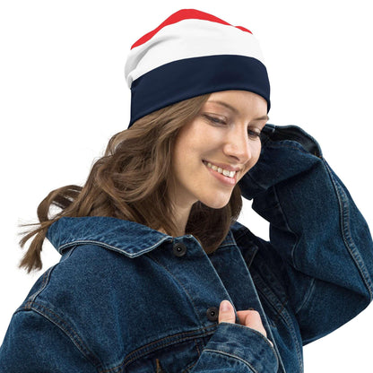 Frau mit dreifarbiger Beanie-Mütze in Rot, Weiß und Dunkelblau, Jeansjacke, weißer Hintergrund