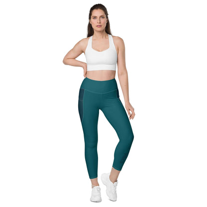 Frau trägt blaue Leggings mit Taschen und weißem Sport-BH auf weißem Hintergrund