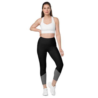 Frau trägt schwarze Leggings mit Taschen, weißem Sport-BH und weißen Turnschuhen vor weißem Hintergrund
