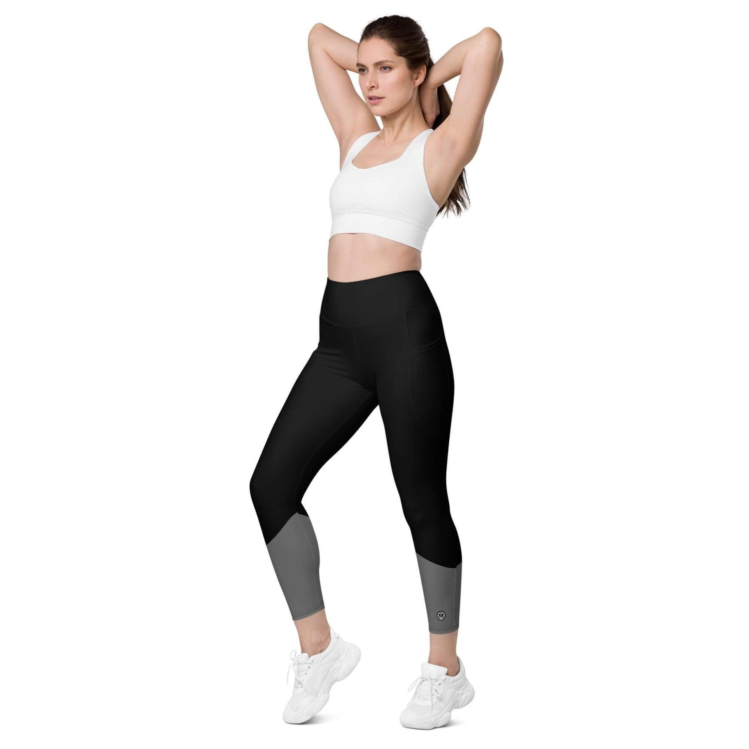 Frau trägt schwarze Leggings mit Taschen und grauen Details, Sportoutfit auf weißem Hintergrund