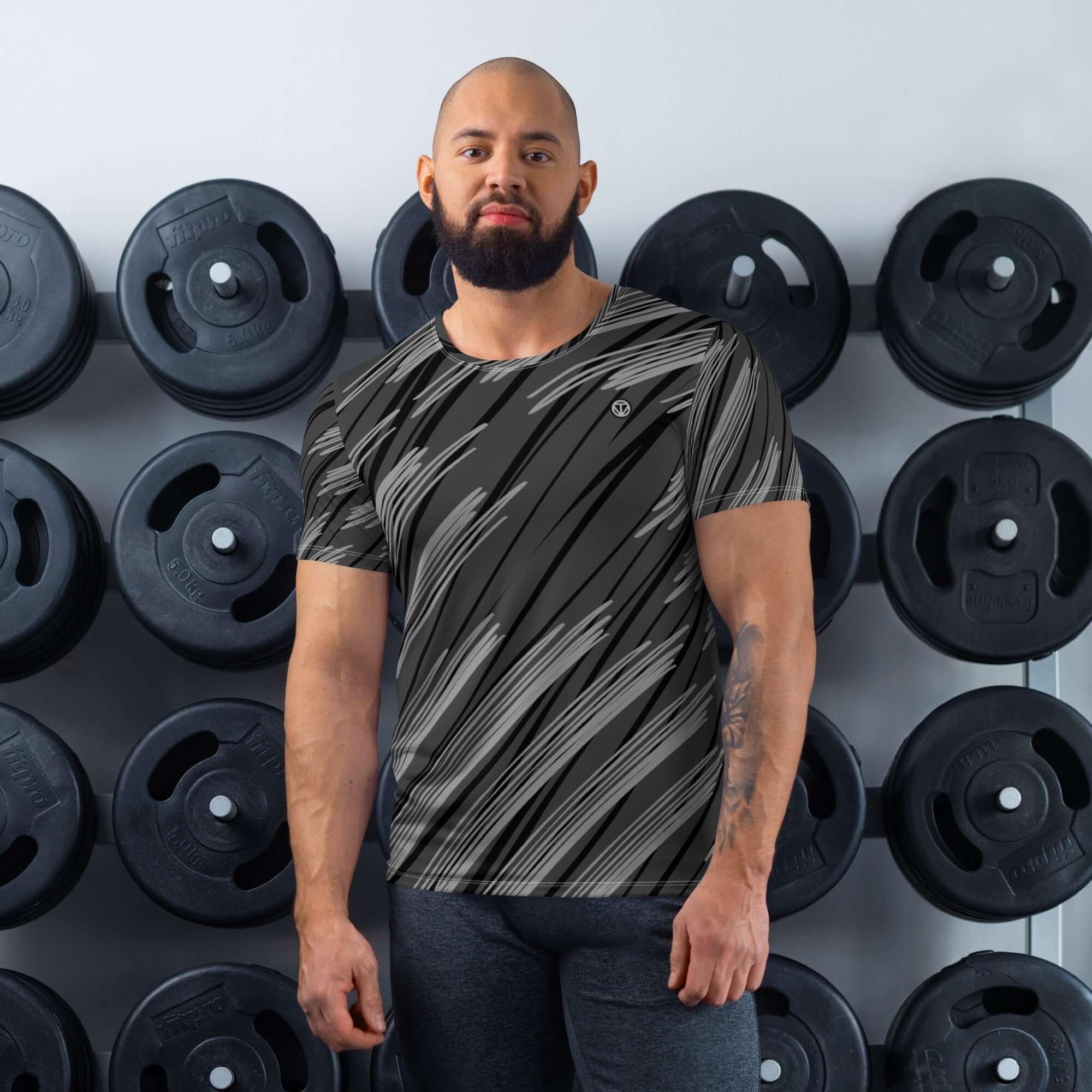 Sportlicher Mann im schwarzen Fitness-T-Shirt mit Muster steht vor Hantelscheiben im Fitnessstudio