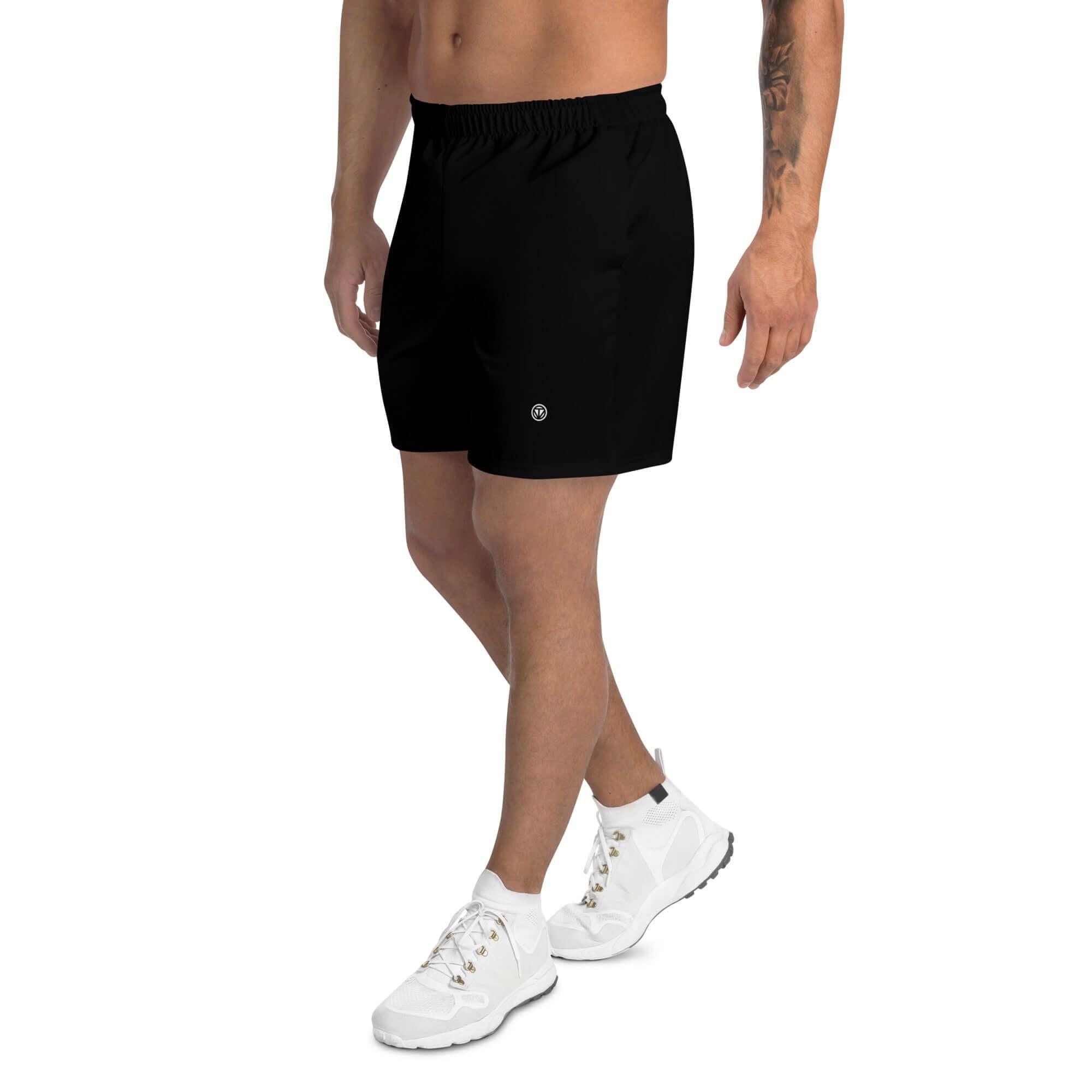 Mann trägt schwarze Herren Trainingsshorts mit weißem Logo und weißen Sportschuhen, Studiohintergrund