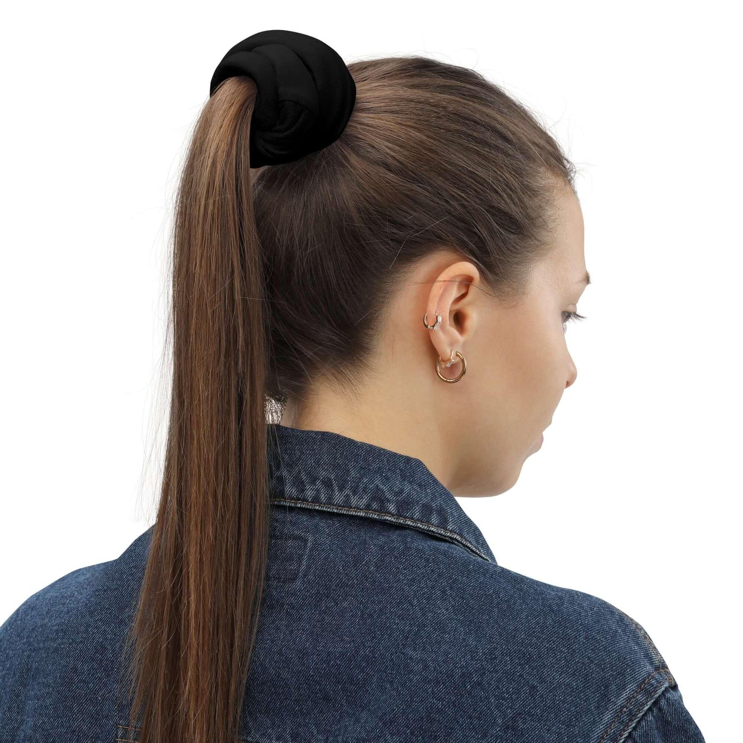 Frau mit braunen Haaren, Zopfgummi und Jeansjacke von hinten, weißer Hintergrund