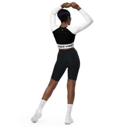Frau trägt langärmliges Crop-Top mit Vibes-Schriftzug, schwarze Leggings, sportlich, Rückansicht