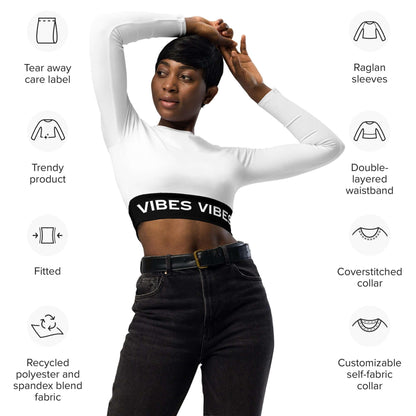 Frau trägt weißes, langärmeliges Crop-Top mit VIBES-Bund, schwarze Jeans, moderner Look