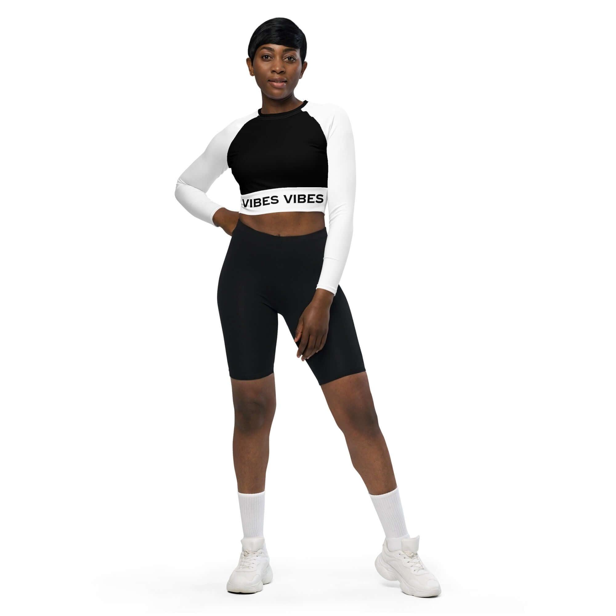 Frau trägt weiß-schwarzes recyceltes Crop-Top mit VIBES-Schriftzug und schwarze Radlerhose