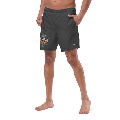 Mann trägt schwarze Badehose mit Logo und Flammenmotiv, seitliche Ansicht vor weißem Hintergrund