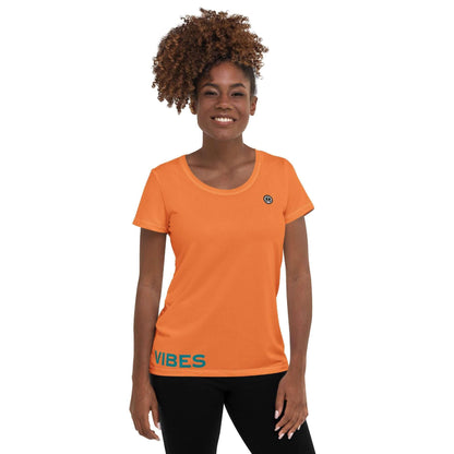 Frau trägt orangenes Damen Sport-T-Shirt mit Vibes-Aufdruck vor weißem Hintergrund.