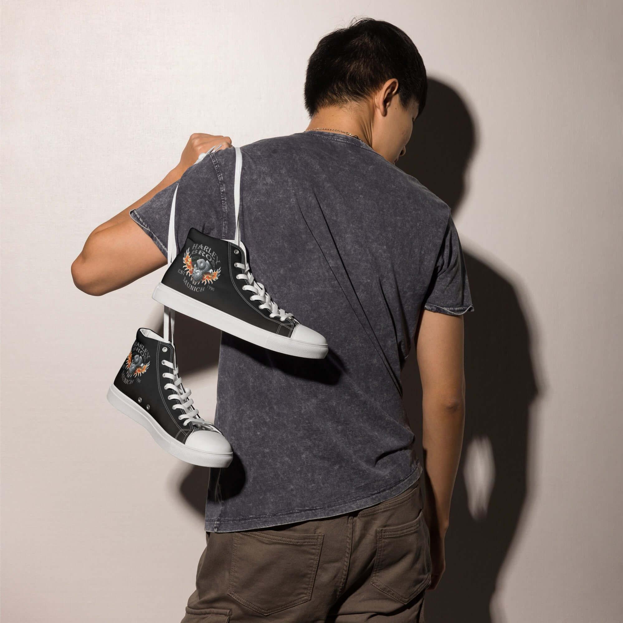 Mann mit schwarzen High-Top-Canvas-Sneakern mit Print-Motiv über der Schulter