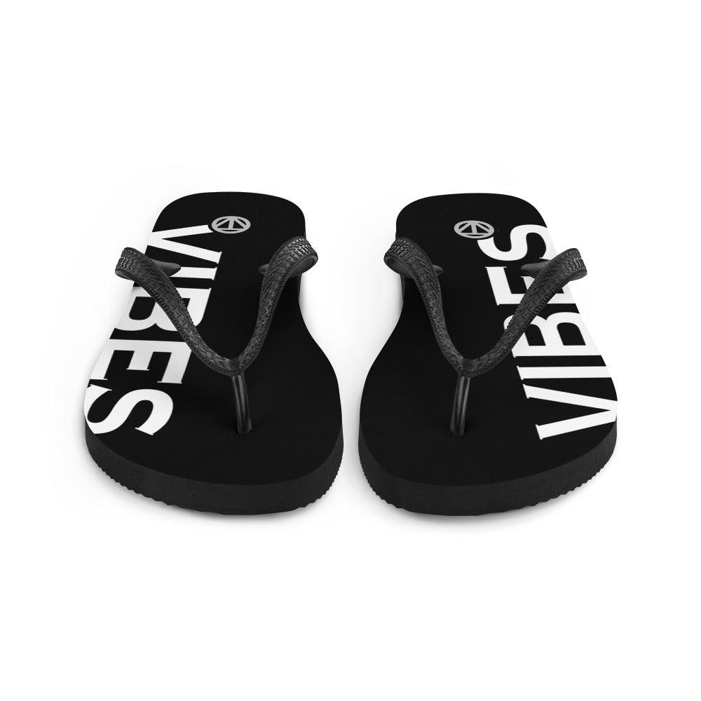 Schwarze Flip Flops mit weißem Vibes-Print und Logo auf der Sohle, Vorderansicht