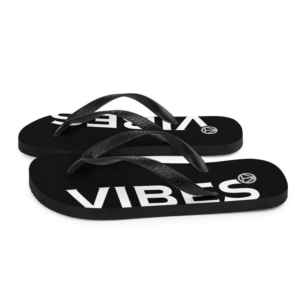 Schwarze Flip Flops mit weißem VIBES-Aufdruck und schwarzem Riemen auf weißem Hintergrund